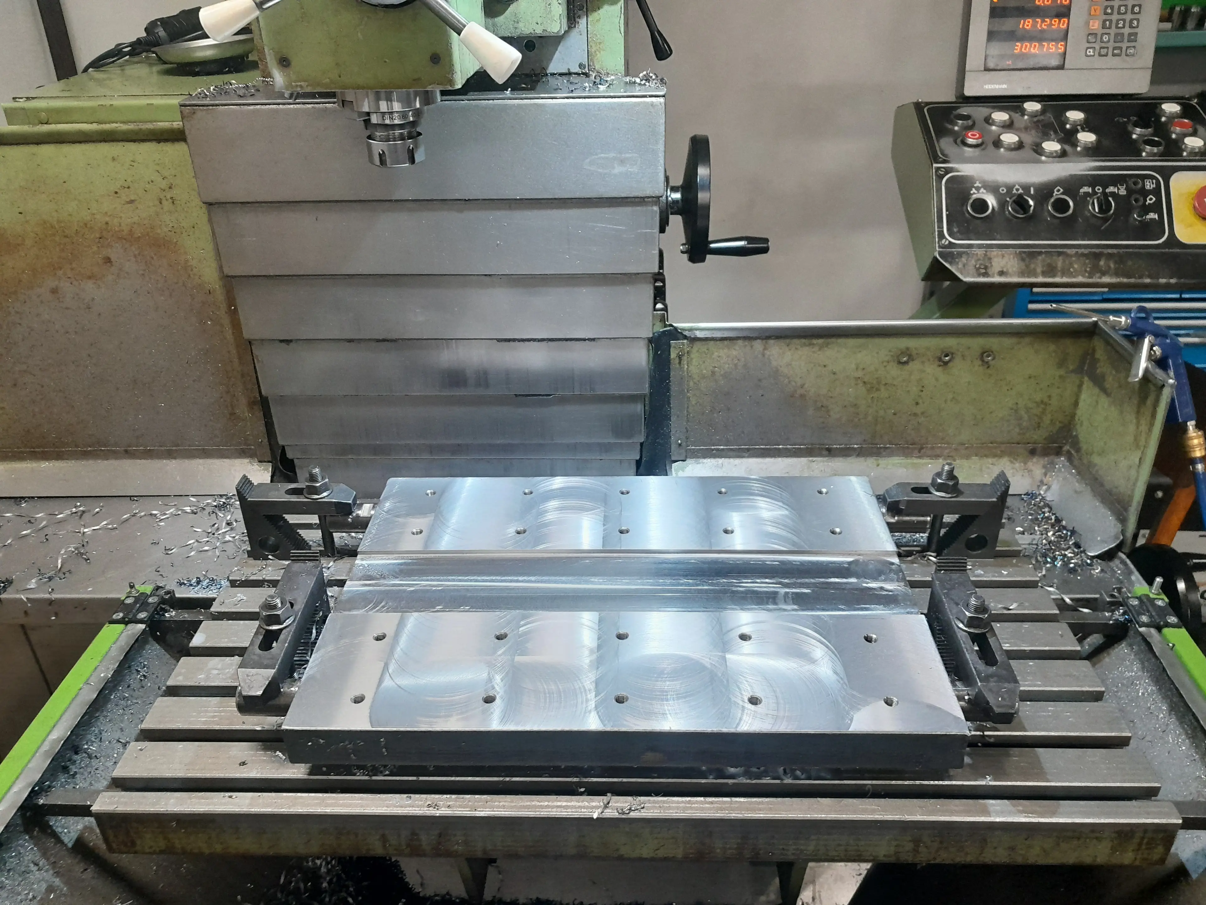 Frézovaná kovová deska upnutá na stole stroje